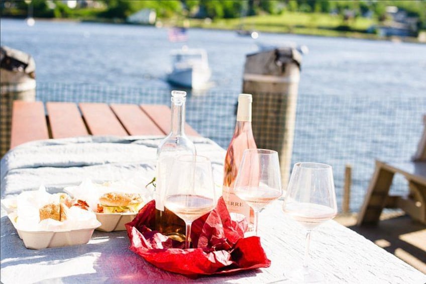 A table with food and wine bottles and glasses by a poolside. 2