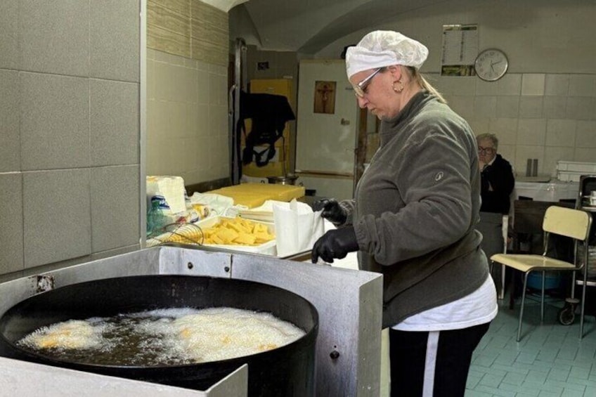 Une personne est en train de faire frire des aliments dans une grande poêle, dans une cuisine. 4