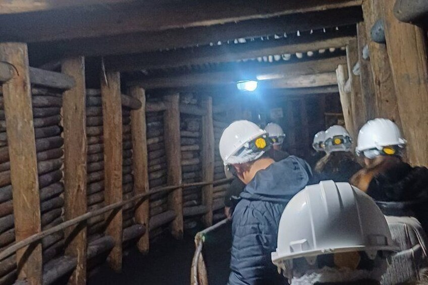 A group of people in hard hats inside a dimly lit, wooden structure with metal beams. 5