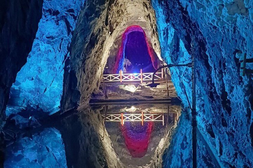 A cave with a reflective water pool and a wooden walkway. 4