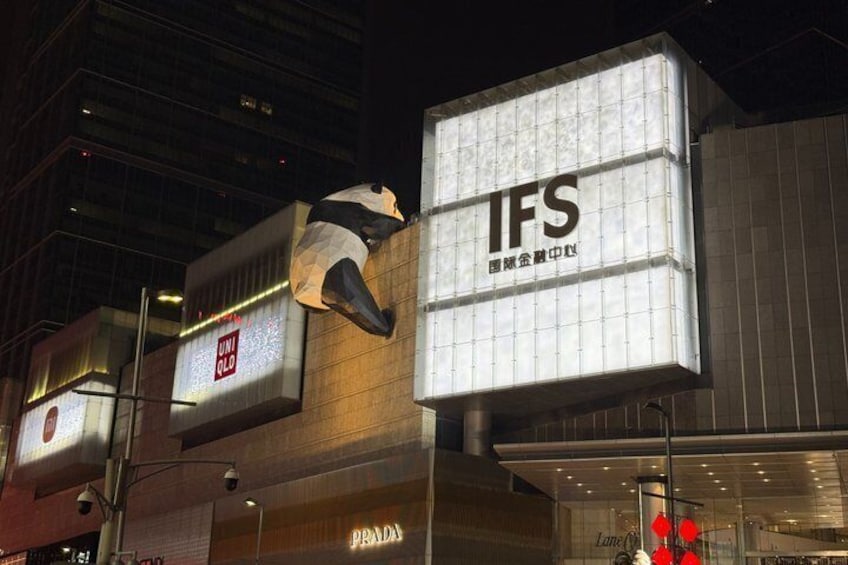 A building with illuminated signs for IFS and Prada, and a large sculpture of a bear. 5