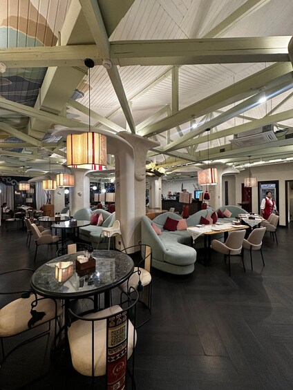A modern interior with high ceilings, hanging lamps, and a mix of seating arrangements including sofas and tables. 4