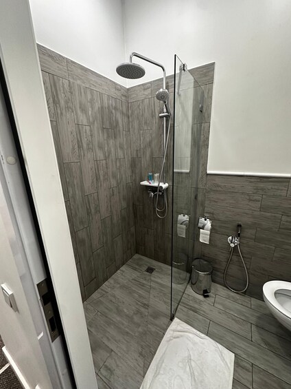A modern bathroom with a glass-enclosed shower, a toilet, and a sink. 2