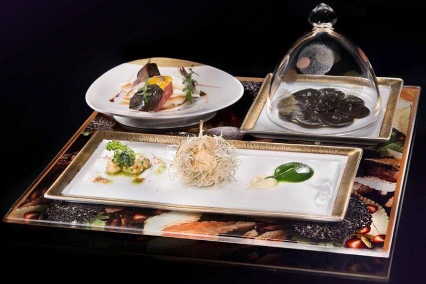Un plato con una variedad de comidas, incluyendo una fuente con tapa transparente. 4