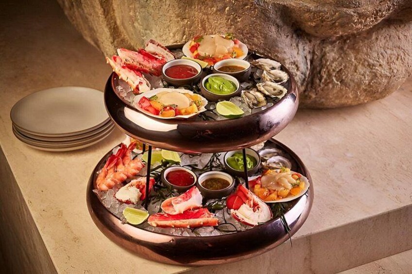 Una bandeja de mariscos con diversos tipos de pescado y mariscos, acompañada de salsas para mojar. 3