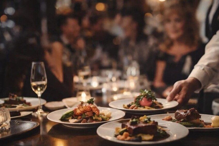 Una mesa de comedor con platos de comida, copas de vino y velas. 1