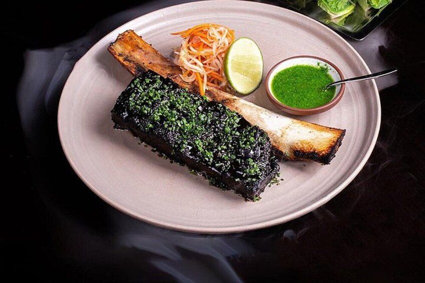 Un plato con un pescado a la parrilla, verduras ralladas, una cuña de lima y una salsa verde. 5