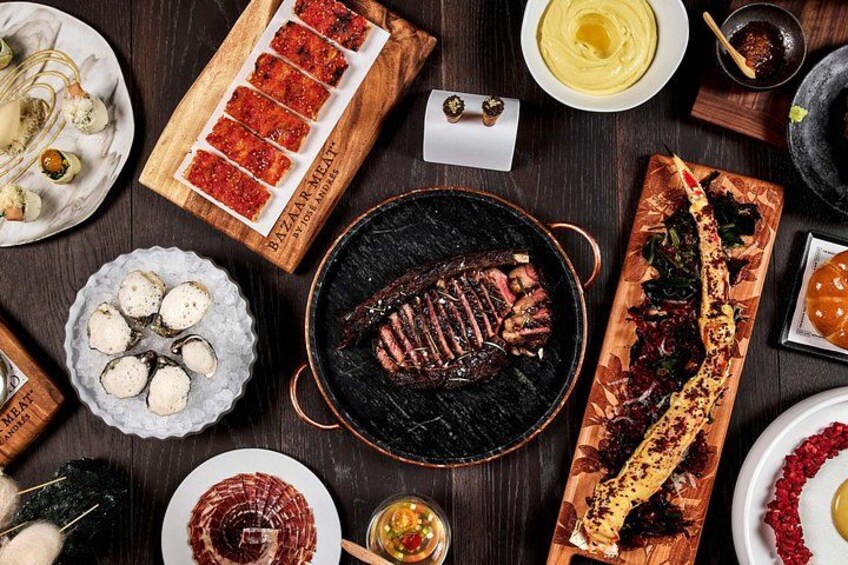 Variedad de platos, incluyendo carne a la parrilla, un pan largo con ingredientes y varios bocados con distintos alimentos. 3