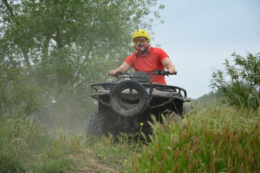 En person kører på en ATV i et græsareal med træer i baggrunden. 4