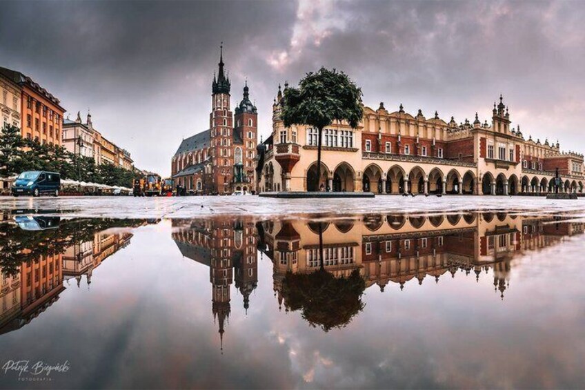 A historic building with a tower, a tree, and a reflection in the water. 2