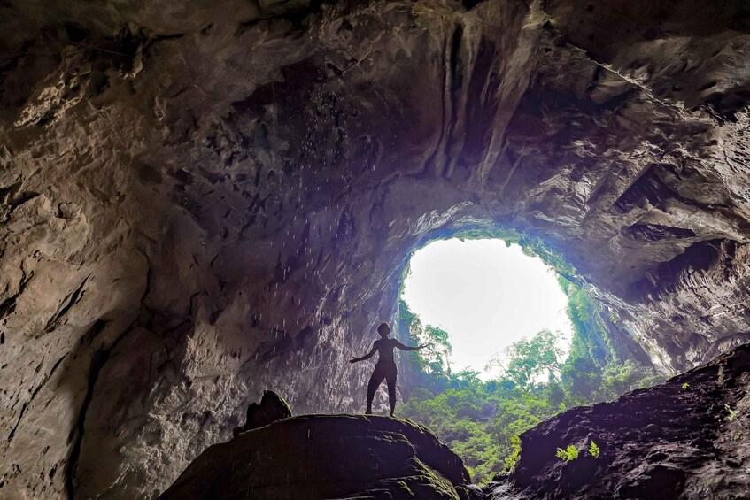 A person standing inside a cave with a natural opening to the outside. 1