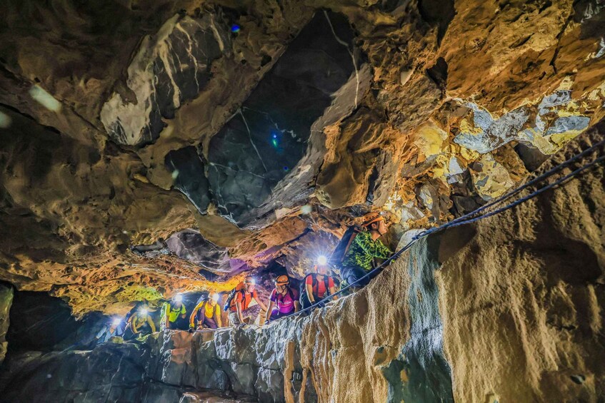 A group of people on a rope bridge inside a cave with illuminated walls. 3