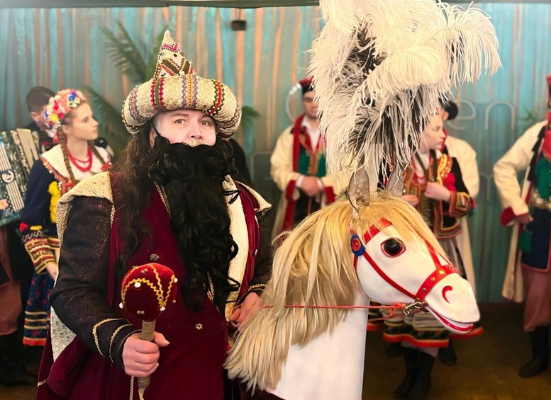 A person in a red robe and a turban, holding a staff, with a horse head mask. 3