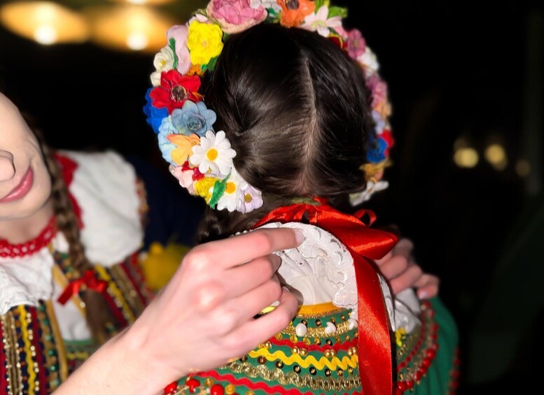 A person wearing a colorful floral headpiece and a traditional garment with a red ribbon. 5