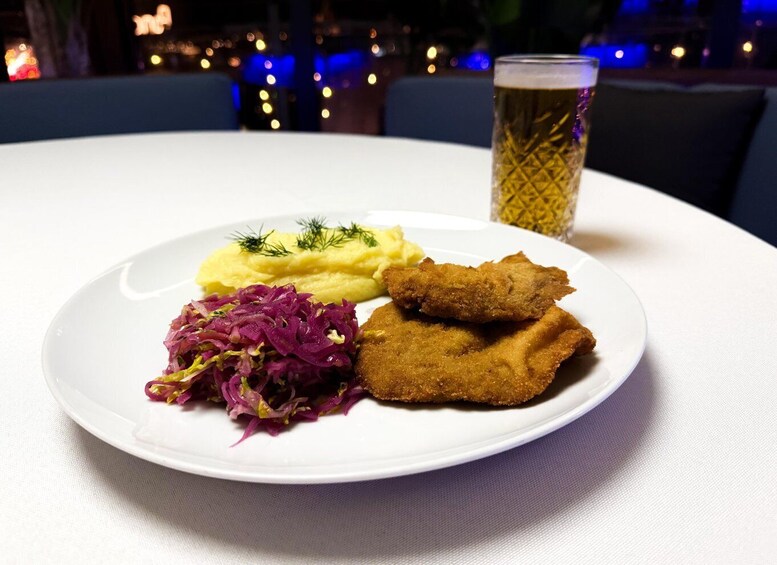 A plate with breaded fish, mashed potatoes, and red cabbage, accompanied by a glass of beer. 2