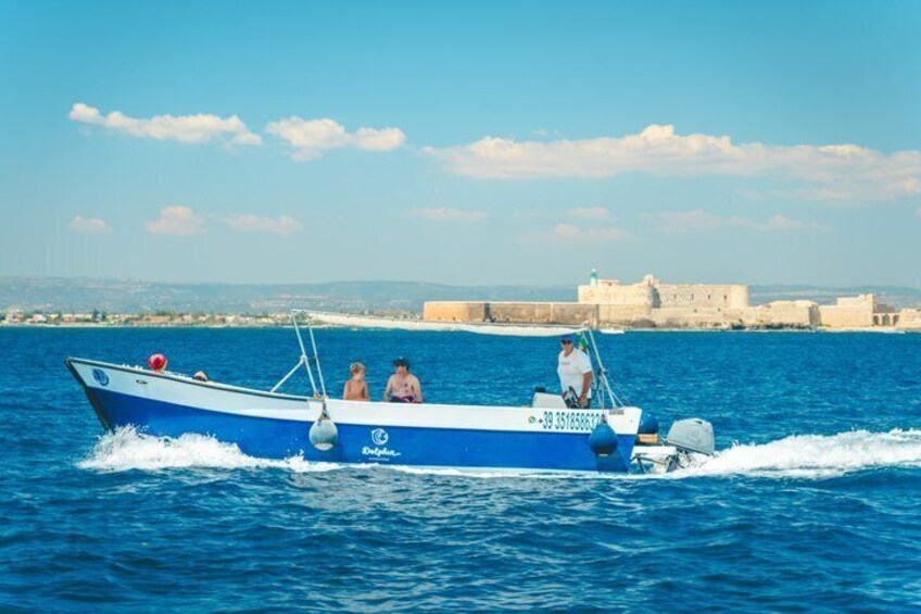 Ein blaues Boot mit Personen fährt durchs Wasser, im Hintergrund ein historisches Gebäude. 5
