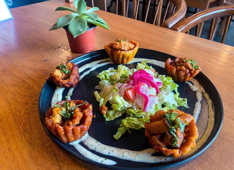 A plate of food with a salad, a potted plant, and a wooden table. 1