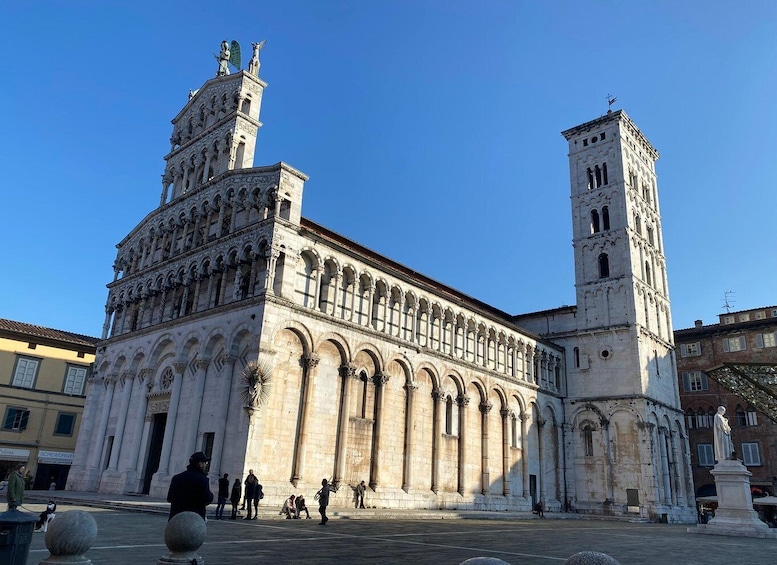 A historic cathedral with two towers, a large arched entrance, and a statue in the foreground. 2