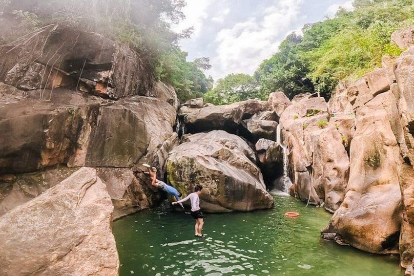 Een rotsachtig landschap met een waterval en een persoon die in het water staat. 1