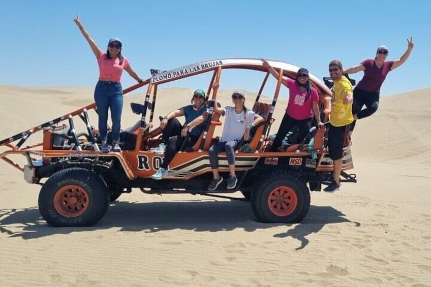 En sandbuggy med passagerare som kör på ett sandigt duneområde. 4