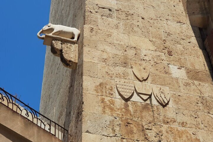 A stone wall with carved animal figures and a metal fence. 4