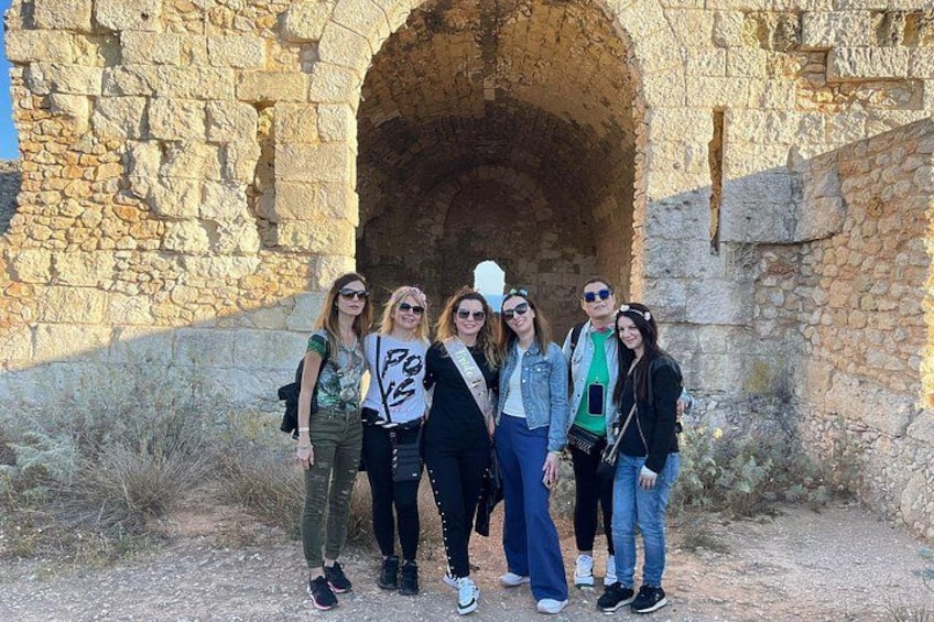 A group of people standing in front of an ancient stone structure with an arched entrance. 3