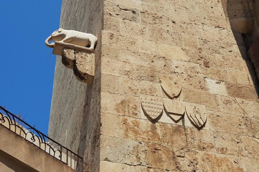 A stone wall with carved animal figures and a metal fence. 3