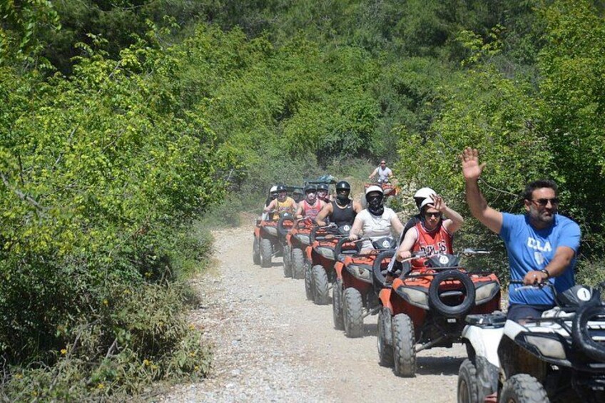 People riding ATVs on a gravel path surrounded by greenery. 2