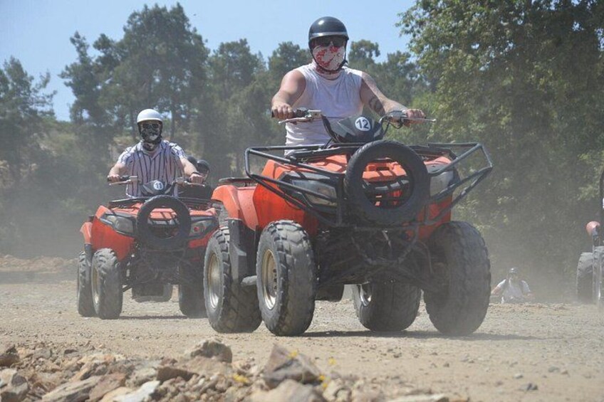 Two people riding atv's on a dirt road. 5
