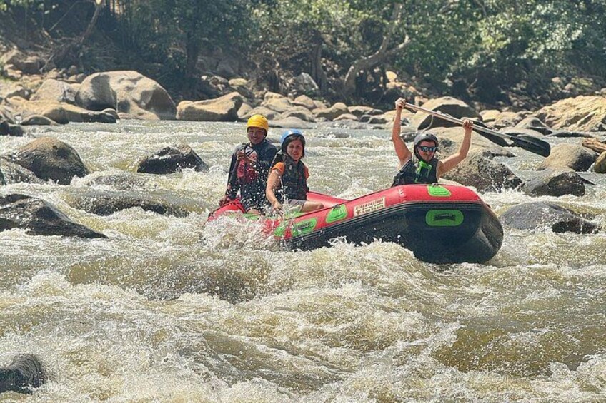 Two people rafting on a river with rapids, surrounded by rocks and trees. 2