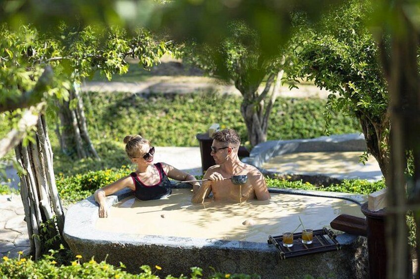 Twee personen ontspannen in een jacuzzi, omringd door groen. 3