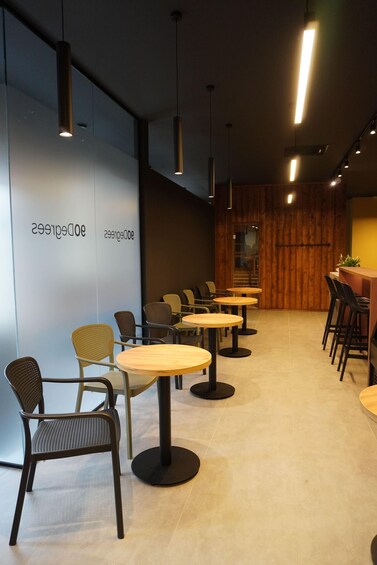 A modern cafe interior with round tables, chairs, and pendant lighting. 4
