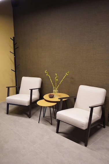 Two white armchairs and a small round table with a vase of green plants. 5