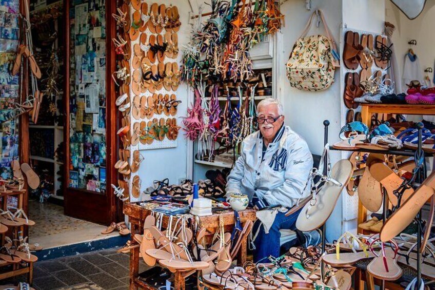 A man in a shop filled with various types of shoes and sandals. 3