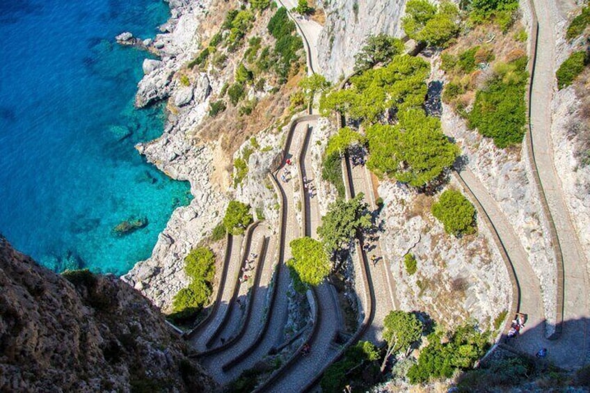 A winding coastal road with rocky terrain and sparse vegetation. 4