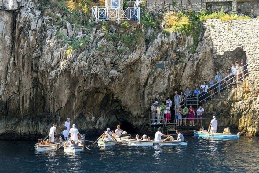 People rowing boats on a river, a stone wall, and a staircase leading to a platform. 5