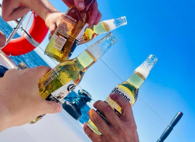People holding bottles of white wine with a clear sky in the background. 1