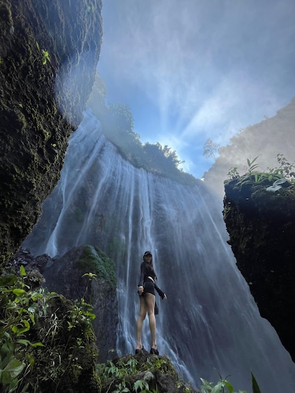 A person standing on a rock with a waterfall in the background. 4