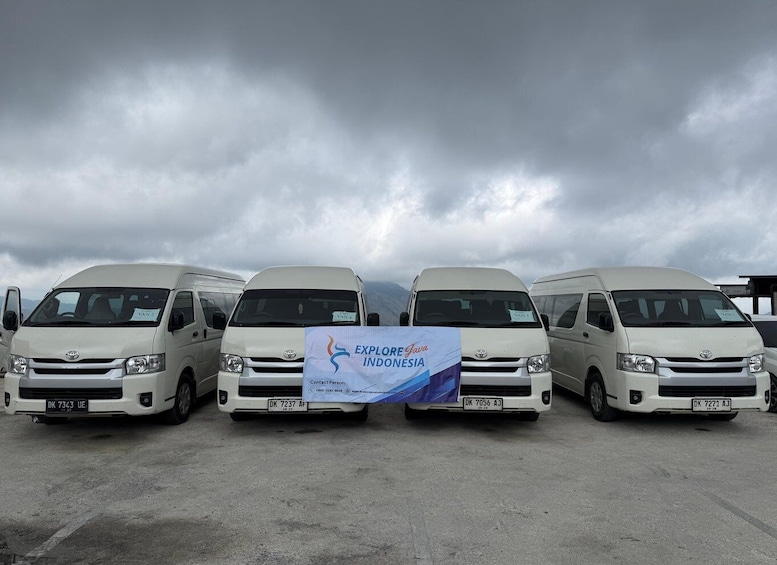 Four white vans parked in a row with a cloudy sky in the background. 5