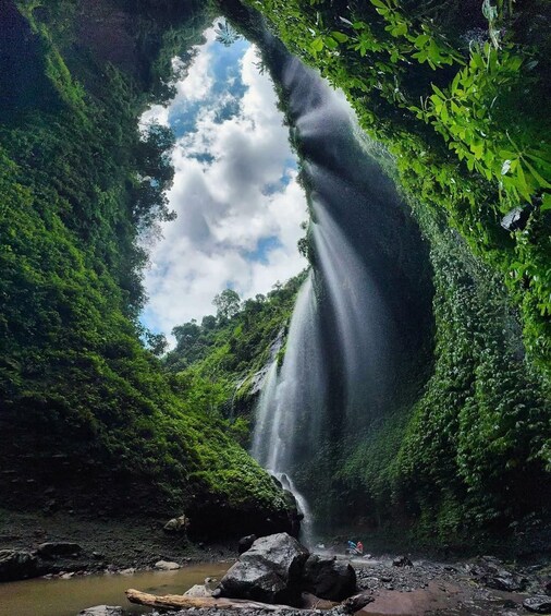 A waterfall in a lush green forest with a clear sky above. 2