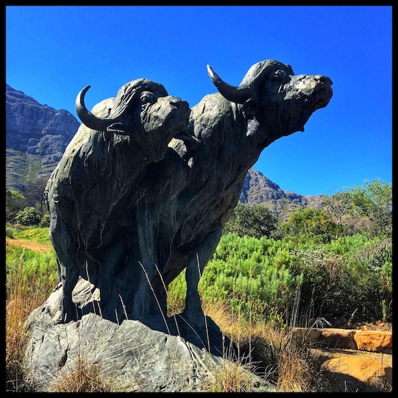 A buffalo statue in a natural landscape with mountains in the background. 1