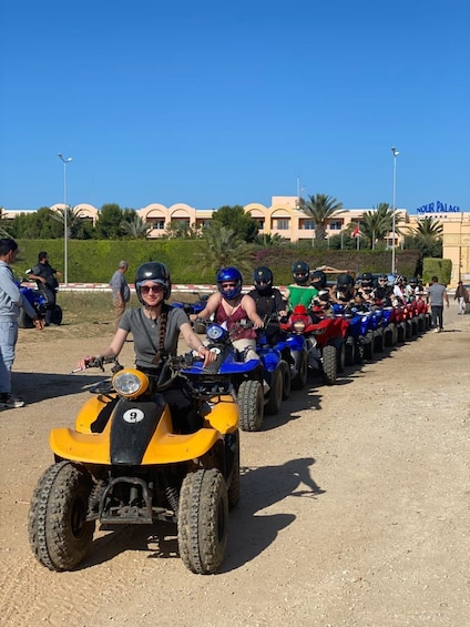 A line of ATVs parked on a dirt road with a building labeled 'NOUR PALACE' in the background. 5