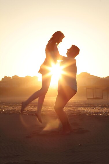 A couple dancing on a beach with the sun setting in the background. 1