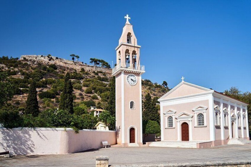 A church with a clock tower and a smaller building, set against a hillside with trees. 3