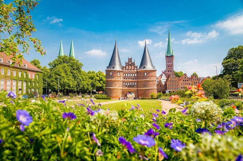 Ein historisches Gebäude mit zwei Türmen, umgeben von üppigem Grün und bunten Blumen. 5