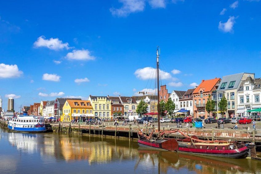 Ein Ufer mit bunten Gebäuden, einem vertäuten Boot und wolkenlosem, blauem Himmel. 2