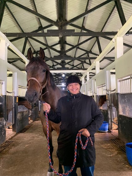 A stable interior with a horse and a person holding a lead rope. 3