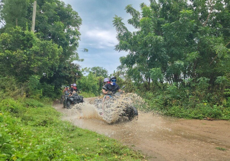 Two off-road vehicles driving through a muddy path surrounded by dense greenery. 5