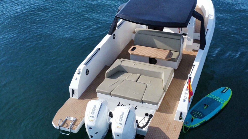A boat with a covered seating area, two outboard motors, and a wakeboard. 2