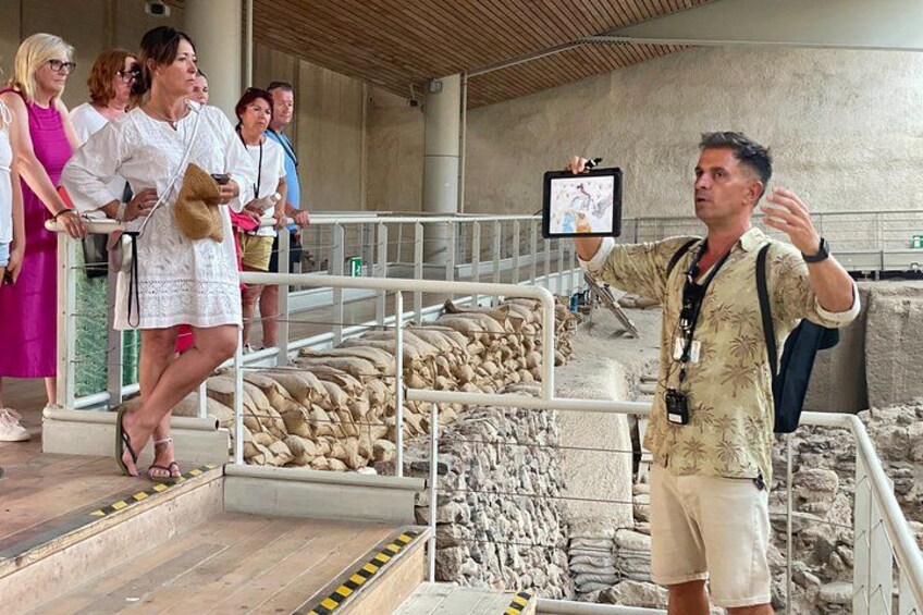 Une exposition de musée présentant des objets anciens, un visiteur prenant une photo et un guide expliquant les pièces exposées. 4